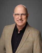 A picture of a man in a suit smiling.
