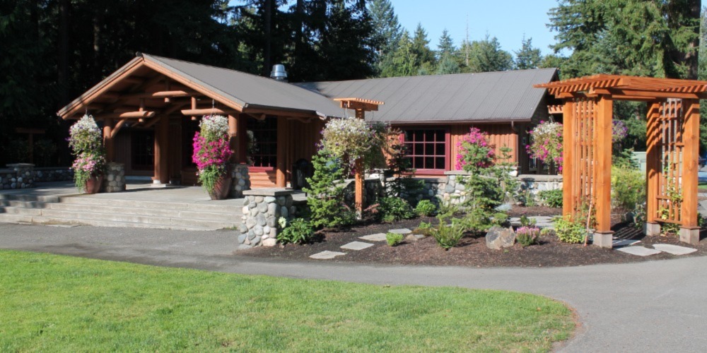 photo of inviting entrance to Beaver Lake Lodge with bright hanging baskets and a garden with stepping stones