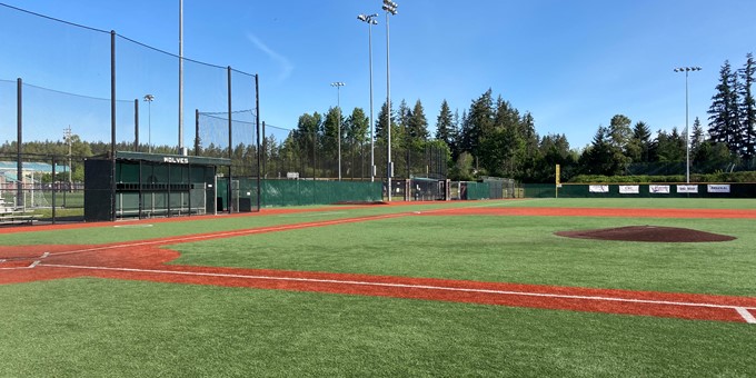 Baseball diamond at Eastlake Community Sports Field 3 in Sammamish with netting, dugout, night lights, and trees in the background.